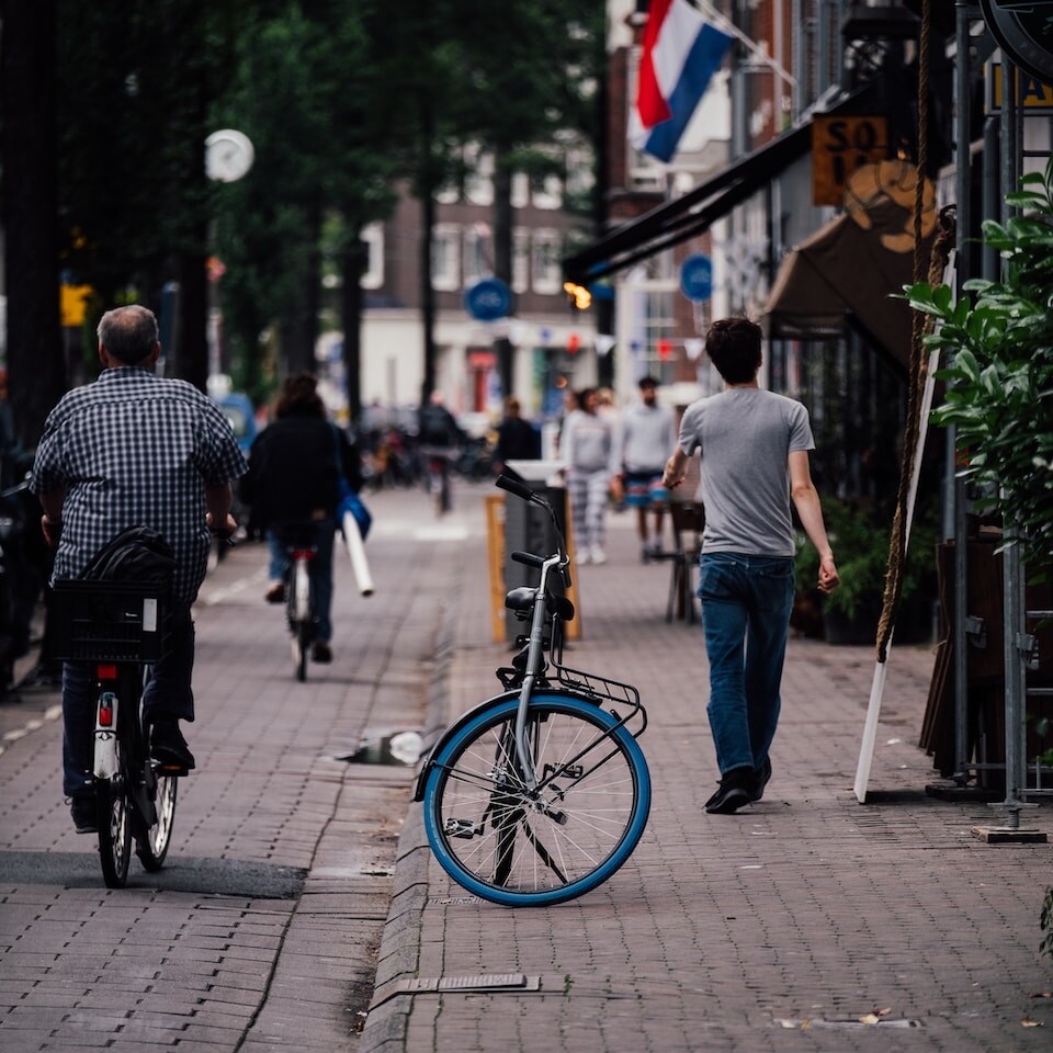 a man walking down a sidewalk next to a bike